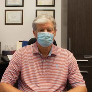 Roger Grochmal sitting in his office wearing a face mask